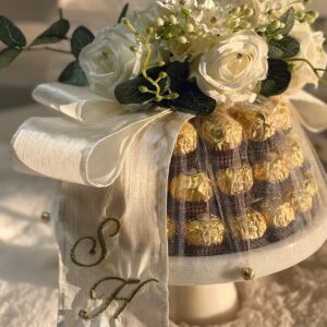 Luxurious Ferrero Rocher tower adorned with white roses and ribbon.