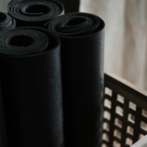 Close-up view of black yoga mats rolled and stacked in a wooden basket indoors.