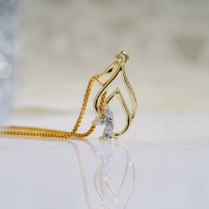 Small precious diamonds in golden shiny pendant on necklace placed on reflective white surface of table