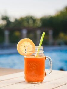 Delicious orange juice in a mason jar with lemon slice by the pool for a refreshing summer drink.