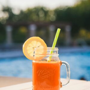 Delicious orange juice in a mason jar with lemon slice by the pool for a refreshing summer drink.