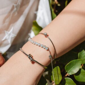 Close-up of elegant silver jewelry on wrist, featuring bracelets and a ring.